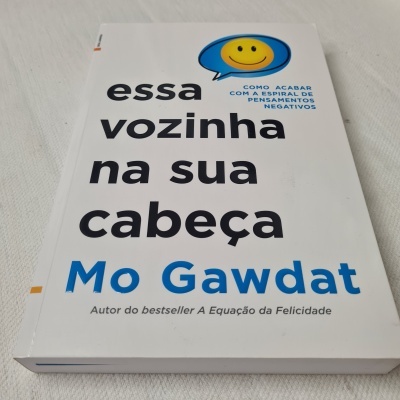 Livro 'essa vozinha na sua cabeça' de Mo Gawdat com balão amarelo e texto em preto e azul
