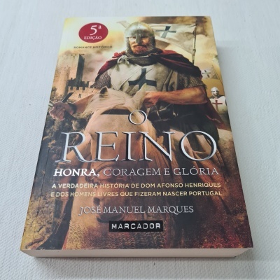 Capa do livro O REINO com cavaleiro medieval montado a cavalo e textos visíveis
