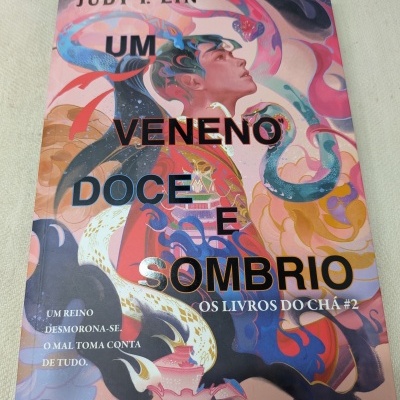 Capa de livro com ilustração de rosto masculino e serpentes coloridas no fundo rosa.