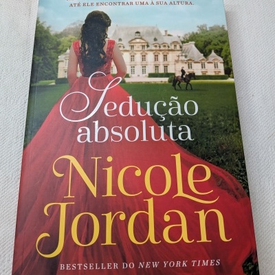 Capa do livro Sedução Absoluta de Nicole Jordan com mulher em vestido vermelho e cavaleiro em mansão