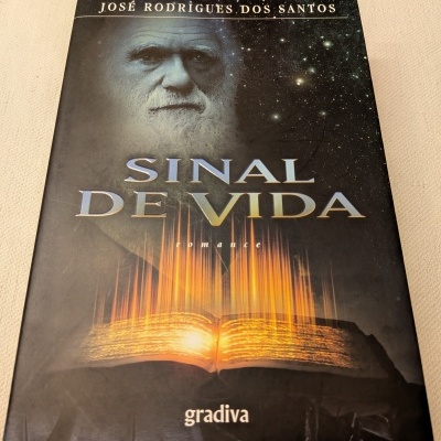 Capa do livro Sinal de Vida de José Rodrigues dos Santos com imagem de livro aberto e rosto idoso