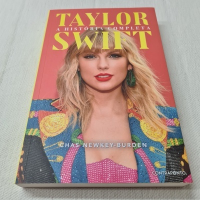 Livro sobre Taylor Swift com capa vermelha e ilustração da cantora