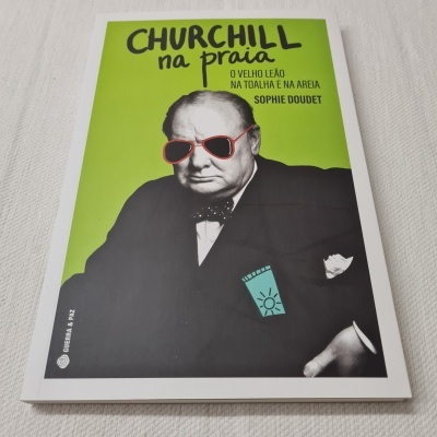 Livro Churchill na praia com capa verde e foto de Winston Churchill com óculos vermelhos