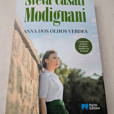 Capa de livro com mulher de saia verde encostada a uma parede de pedra