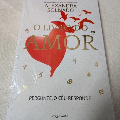 Capa de livro branco com coração vermelho e pássaros, título e texto em letras douradas e pretas