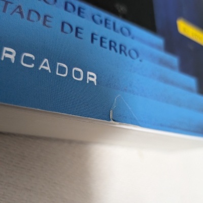 Capa de livro azul com texto em português e desgaste no canto