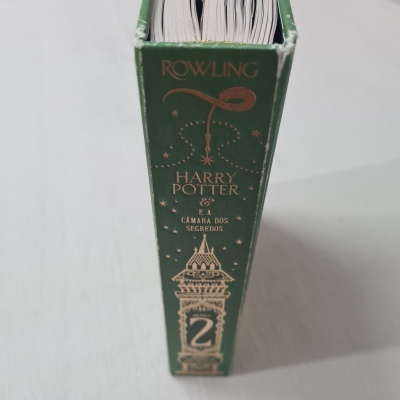 Livro de capa dura verde com detalhes dourados, título Harry Potter e a Câmara dos Segredos.