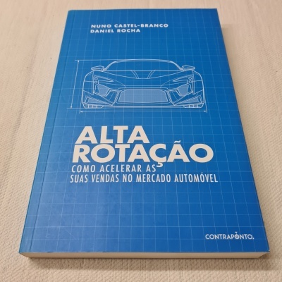Livro azul com desenho de carro e texto em branco sobre vendas no mercado automóvel