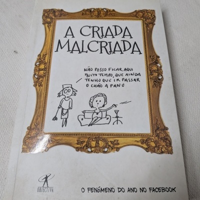Livro A Criada Malcriada com capa branca e moldura dourada desenhada