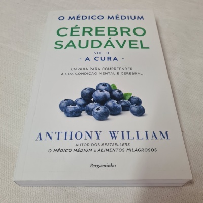Livro 'O MÉDICO MÉDIUM CÉREBRO SAUDÁVEL VOL. II A CURA' com capa branca e mirtilos