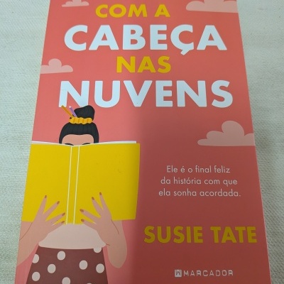 Capa de livro cor-de-rosa com título em letras grandes e ilustração de mulher a ler livro amarelo