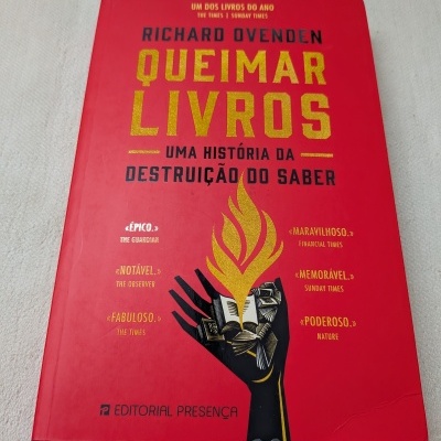 Capa vermelha de livro QUEIMAR LIVROS Uma história da destruição do saber com mão preta segurando livro a arder.