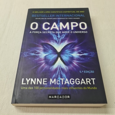Livro 'O CAMPO' de Lynne McTaggart com capa roxa e imagem abstrata azul