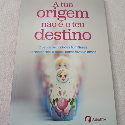 Capa do livro A tua origem não é o teu destino com bonecas russas desenhadas.