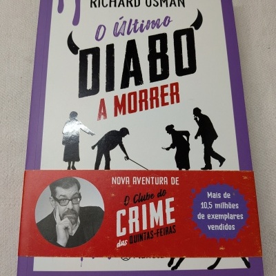 Capa de livro com design em roxo, branco, vermelho e preto com texto e figuras de pessoas a investigar.