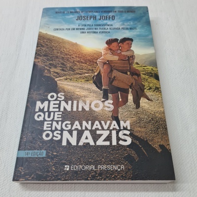 Capa do livro 'Os Meninos Que Enganavam os Nazis' com homem a carregar criança nas costas em paisagem rural