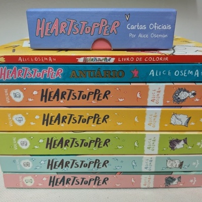 Livros da coleção Heartstopper empilhados por Alice Oseman com diferentes capas coloridas.
