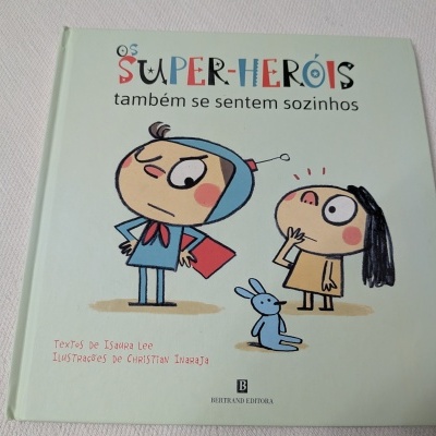 Livro infantil Os SUPER-HERÓIS também se sentem sozinhos com ilustrações de crianças e um coelho azul.