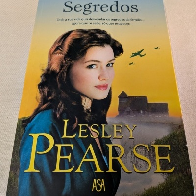 Capa do livro Segredos de Lesley Pearse com mulher e aviões no céu