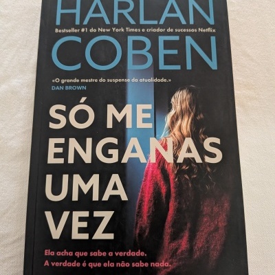 Capa de livro preto com texto azul, branco e rosa, e imagem de mulher de costas com casaco vermelho