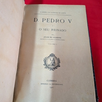 Livro antigo D. Pedro V aberto com texto de 1921 em fundo vermelho