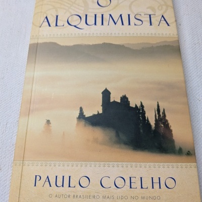 Capa do livro O Alquimista de Paulo Coelho com paisagem enevoada