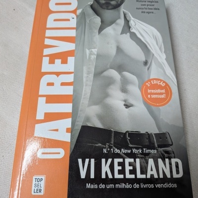 Capa de livro O Atrevido com foto de homem sem camisa e detalhes em laranja