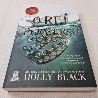 Capa do livro 'O Rei Perverso' com coroa dourada em água