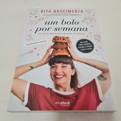 Capa do livro 'um bolo por semana' de Rita Nascimento com a autora sorrindo e bolos sobre a cabeça