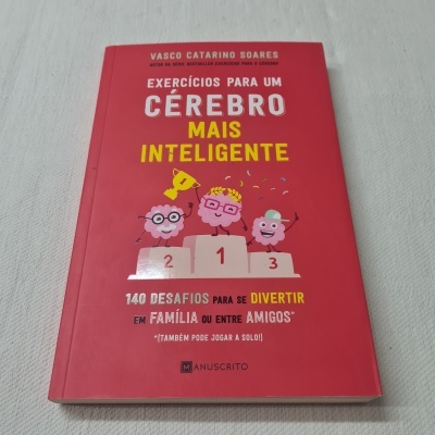 Livro vermelho 'Exercícios para um Cérebro Mais Inteligente' com ilustração de cérebros animados num pódio