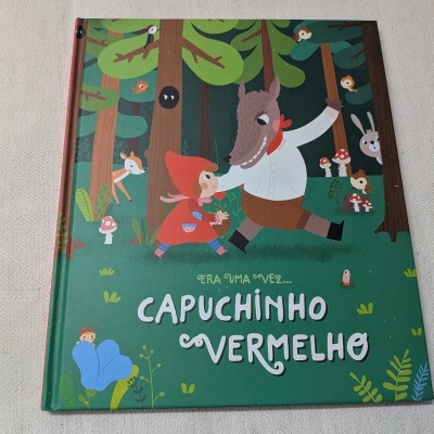 Livro infantil Capuchinho Vermelho com capa verde e ilustração de floresta