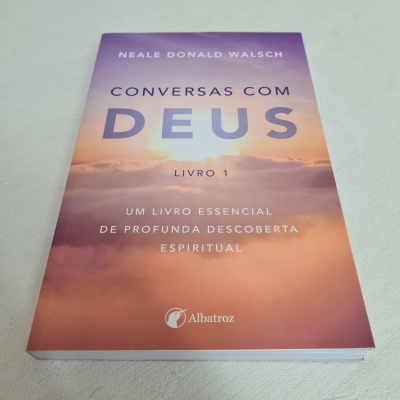 Capa do livro 'Conversas com Deus, Livro 1' com céu ao pôr do sol em tons roxos e laranja.