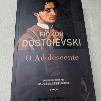 Capa do livro O Adolescente de Fiódor Dostoiévski com retrato de um jovem e texto editorial
