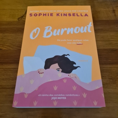 Livro 'O Burnout' de Sophie Kinsella com capa laranja e lilás e ilustração de mulher