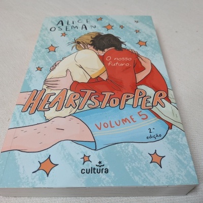 Capa do livro Heartstopper Volume 5 com duas personagens abraçadas e texto em balão vermelho.