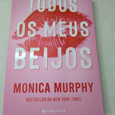 Capa de livro rosa com título em branco e vermelho e impressão de batom vermelho