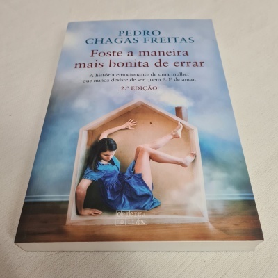 Capa de livro com título, autor e imagem de mulher dentro de casa de madeira