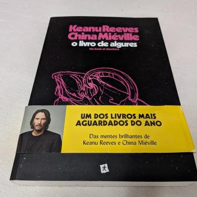 Livro de capa preta com título em rosa e faixa amarela com texto promocional e foto de homem