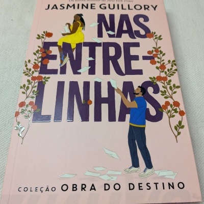 Capa de livro rosa claro com título NAS ENTRE-LINHAS e ilustrações de duas pessoas e flores