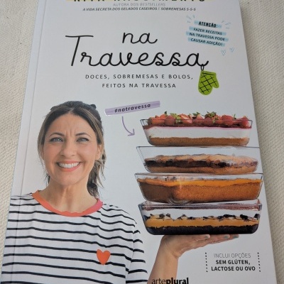 Capa de livro Na Travessa com mulher sorridente e travessas de sobremesas empilhadas