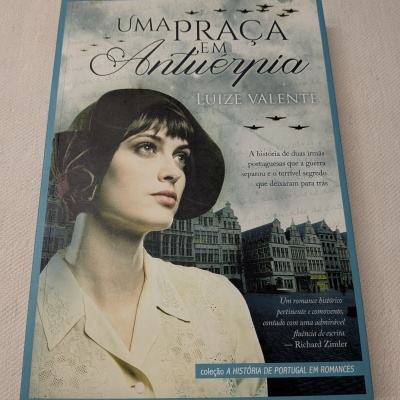 Capa do livro Uma Praça em Antuérpia com mulher, aviões e edifícios históricos