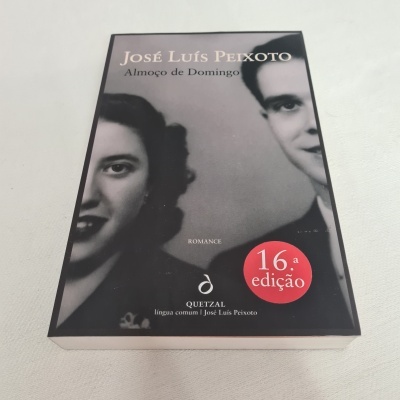 Capa de livro preto com foto preto e branco de duas pessoas e selo vermelho da 16.ª edição