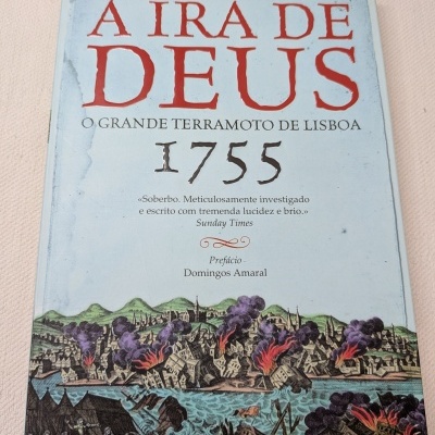 Capa de livro A IRA DE DEUS O GRANDE TERRAMOTO DE LISBOA 1755 com ilustração de cidade em chamas.