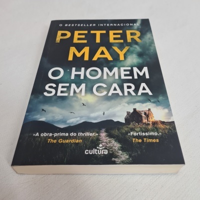 Livro 'O HOMEM SEM CARA' de Peter May com capa escura e imagem de paisagem com casa.