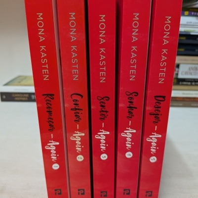 Cinco livros vermelhos empilhados com os títulos e autora visíveis.