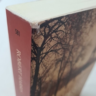 Livro com lombada vermelha e capa com imagem de árvores ao entardecer