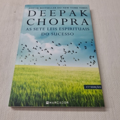 Capa do livro 'As sete leis espirituais do sucesso' de Deepak Chopra com campo verde e pássaros