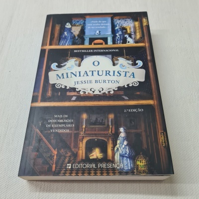 Capa do livro 'O Miniaturista' com design de casa de bonecas e texto em português