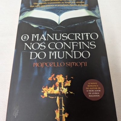 Capa de livro com título O MANUSCRITO NOS CONFINS DO MUNDO e cruz em chamas