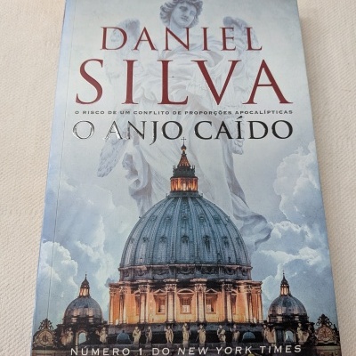 Capa do livro O Anjo Caído de Daniel Silva com imagem de anjo estátua e edifício